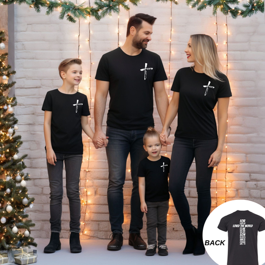 Family of four wearing matching black t-shirts with John 3 16 in a white design, standing in front of a decorated Christmas tree and string lights.