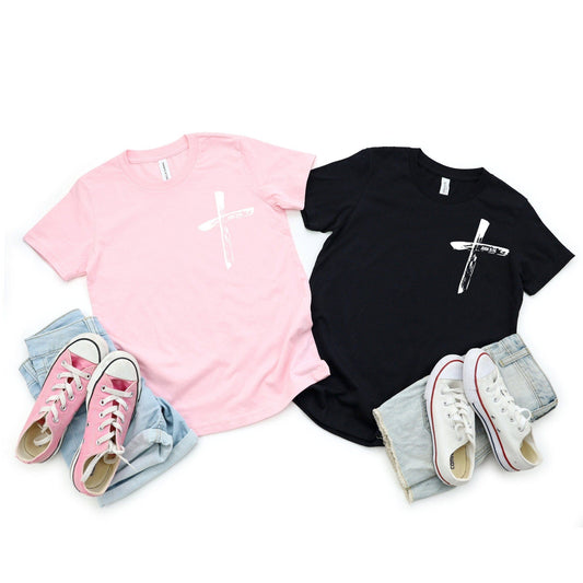 Two black and pink Camiseta Infantil Juan 3:16 with cross design; front features a brush-stroke cross, and back displays John 3:16 verse in Spanish.