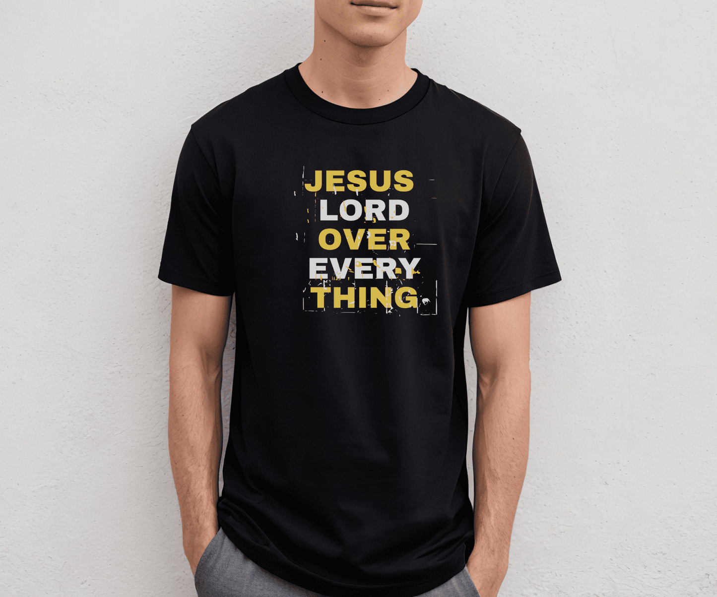 Black Jesus Lord Over Everything shirt with bold yellow and white distressed text reading “Jesus Lord Over Everything,” modeled by a man against a plain wall.