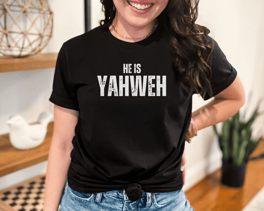 Smiling women wearing black Christian t-shirts with bold white text that reads “He Is Yahweh,” styled for a modern faith-based look.