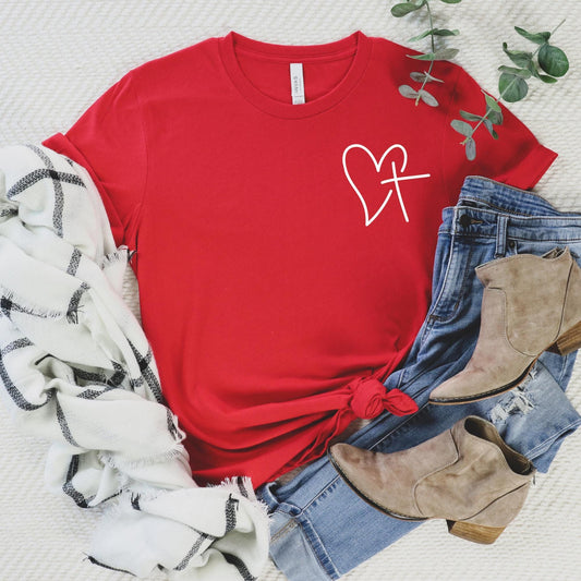 Red Christian t-shirt featuring a heart and cross design, worn by a woman, styled with romantic Valentine’s decor – a perfect faith-based gift for women.