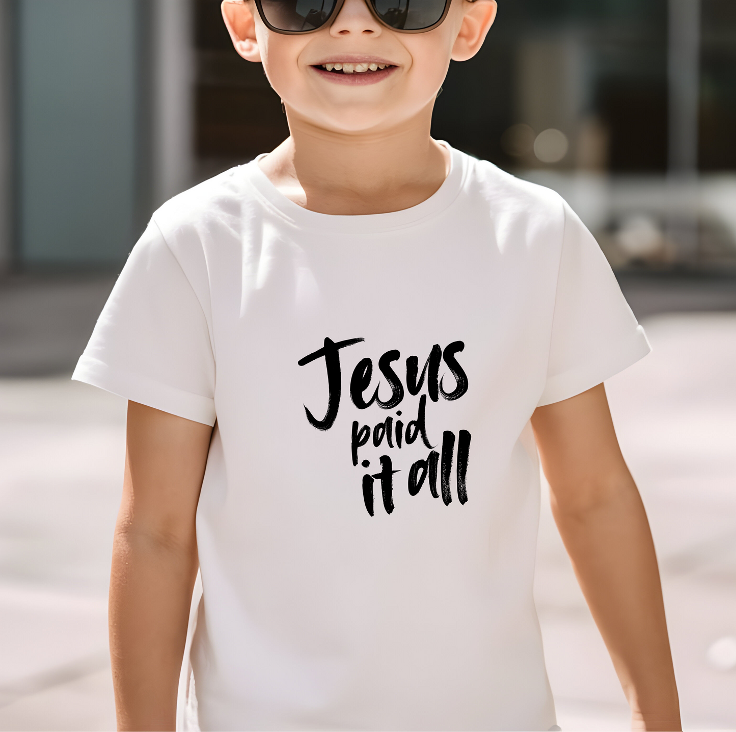  Young boy smiling wearing Jesus Paid It All kids Christian t-shirt in white by Abound in Faith