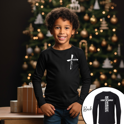 Child wearing a black long-sleeve shirt john 3 16 with a white design in front of a decorated Christmas tree.