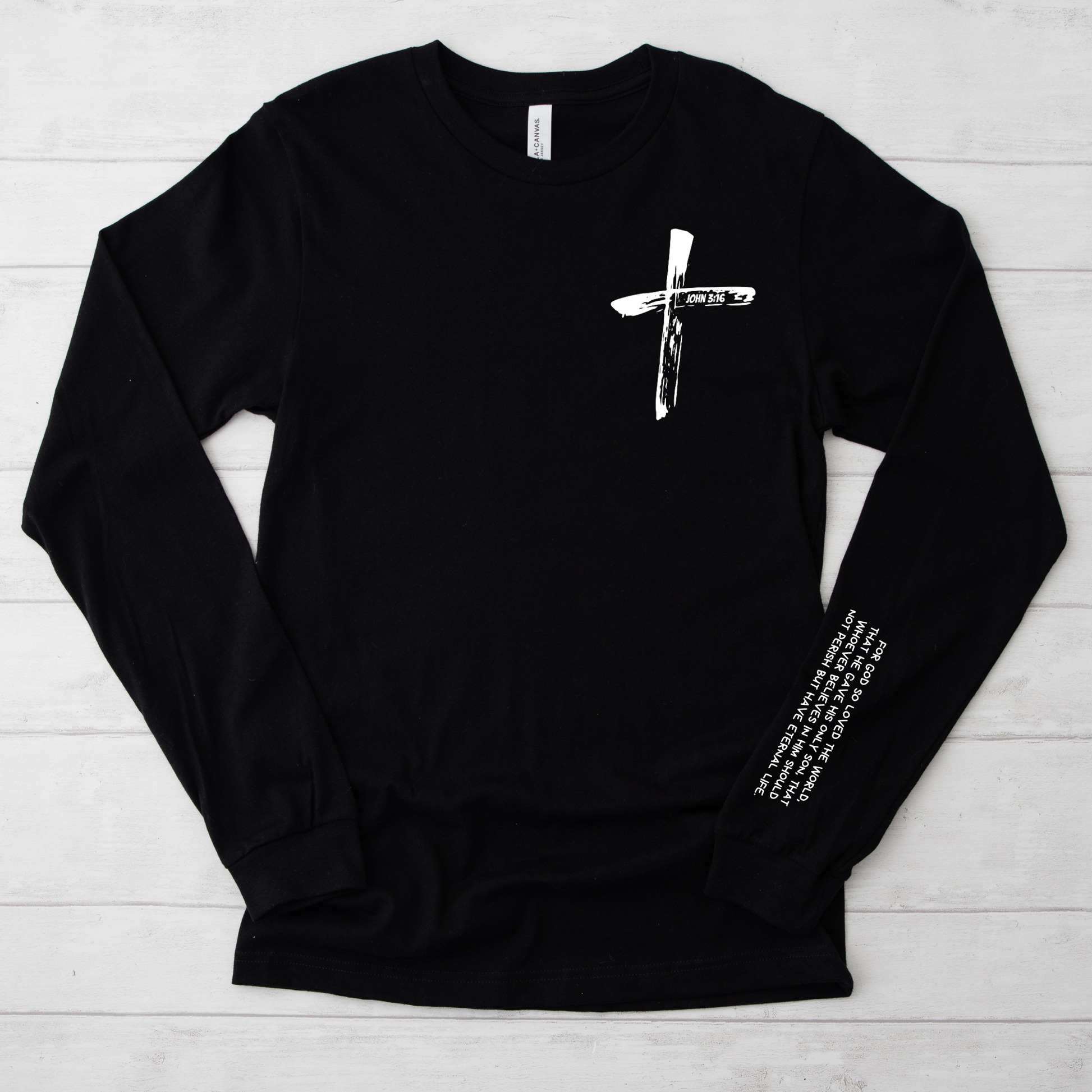 Black long-sleeve shirt john 3 16 bible verse in a cross white cross design on a light wooden surface
