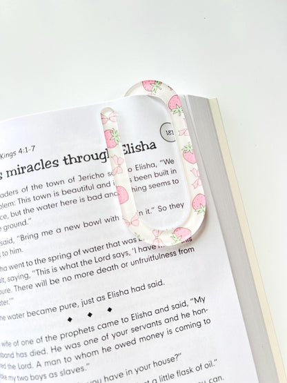 Clear acrylic bookmark with pink strawberry pattern clipped onto an open Bible at 2 Kings 4
