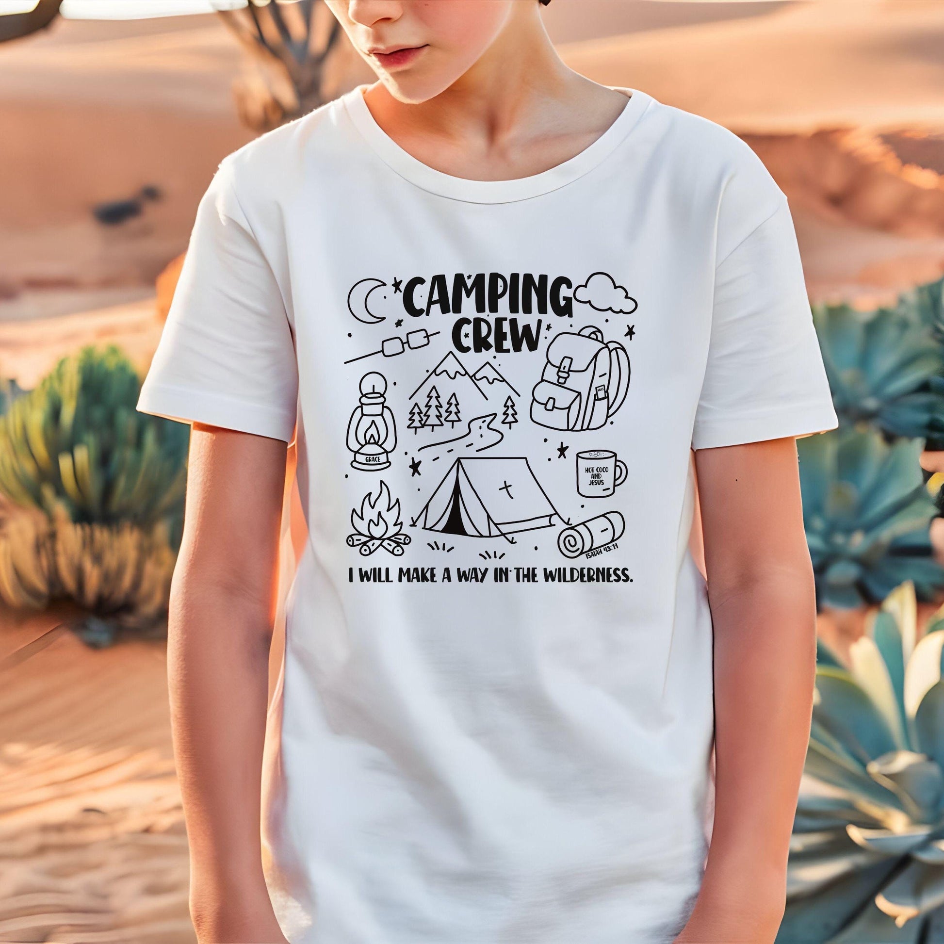 Child wearing a white Camping Crew Christian Shirt for Kids with colorful Camping Crew design featuring a tent, trees, and verse that reads I will make a way in the wilderness in white