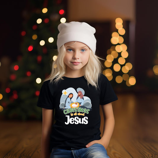 Girl wearing a Black Christmas Is All About Jesus Kids T-Shirt with nativity illustration and ‘Christmas is all about Jesus’ text, ideal for faith-based holiday outfits.