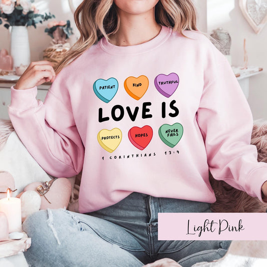 Pink Christian sweatshirt for women with colorful Love Is design based on 1 Corinthians 13:4 Bible verse