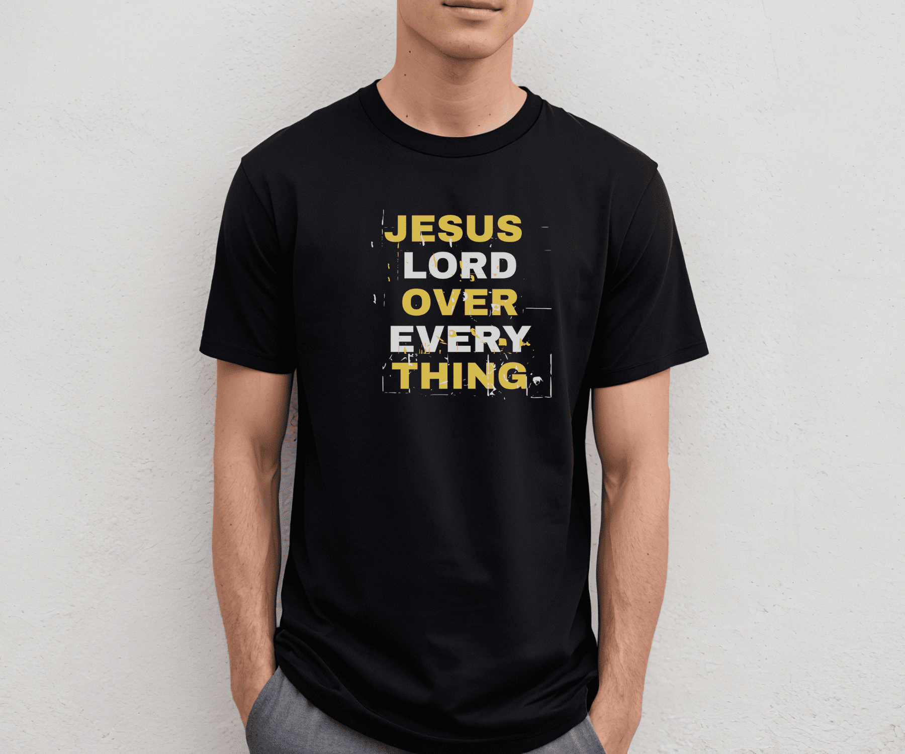 Black Jesus Lord Over Everything shirt with bold yellow and white distressed text reading “Jesus Lord Over Everything,” modeled by a man against a plain wall.