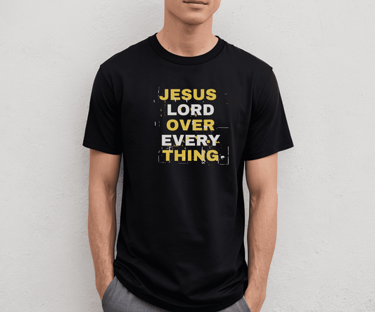 Black Jesus Lord Over Everything shirt with bold yellow and white distressed text reading “Jesus Lord Over Everything,” modeled by a man against a plain wall.