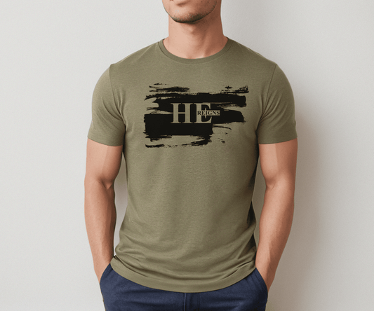 Man wearing a heather olive He Reigns Shirt with bold black brushstroke and “He Reigns” text, inspired by Psalm 9:7.