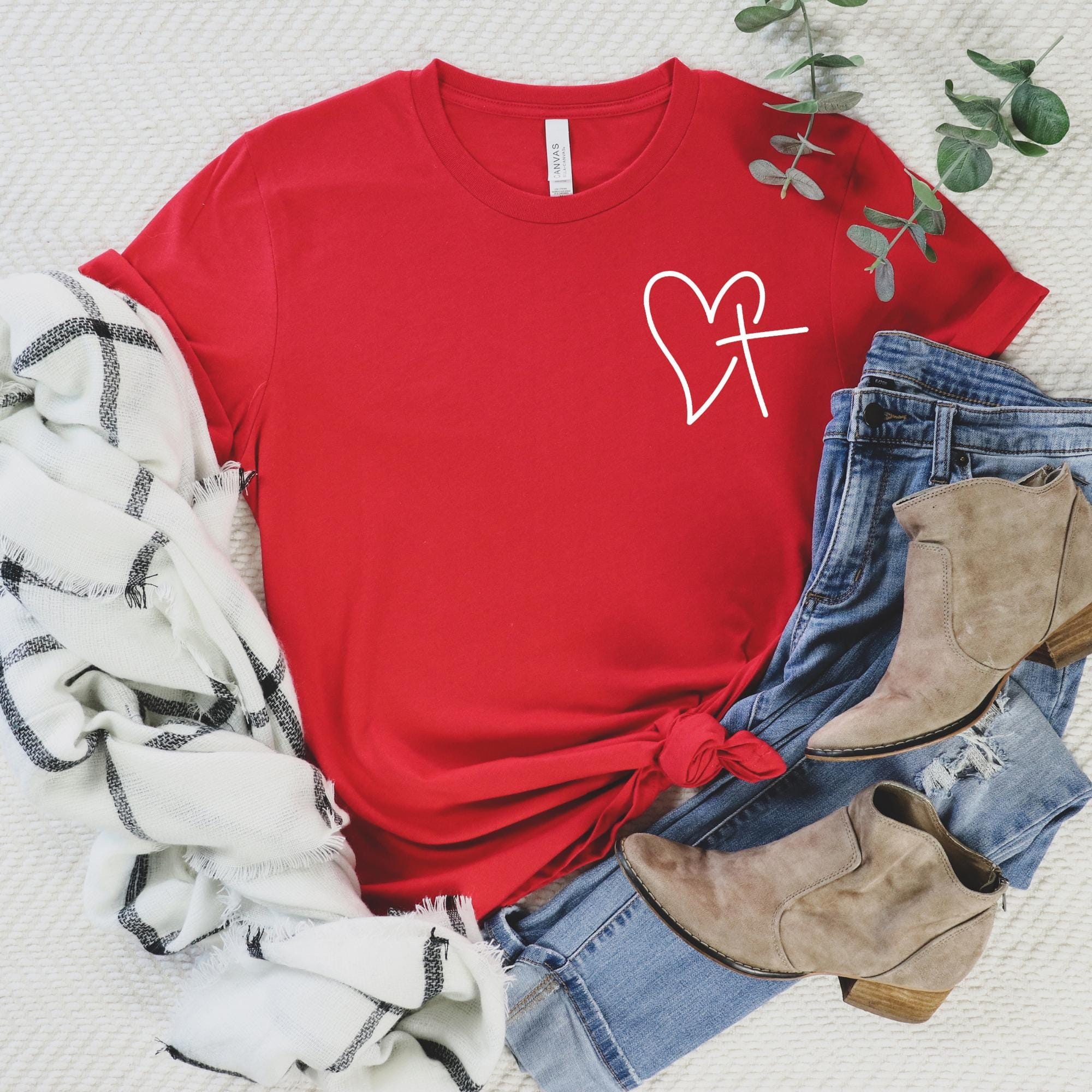 Red Christian t-shirt featuring a heart and cross design, worn by a woman, styled with romantic Valentine’s decor – a perfect faith-based gift for women.